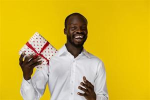 hombre feliz sonriendo a la cámara y sosteniendo un regalo foto