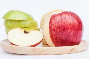 Manzanas en una placa de madera sobre un fondo blanco. foto