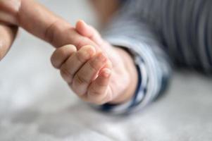 la mano del bebé recién nacido sostiene los dedos de la madre foto