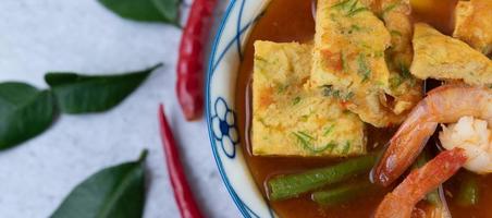 Hot and sour soup with cha-om, egg, and shrimp photo