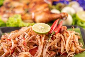 Thai papaya salad surrounded by vegetables and chicken photo