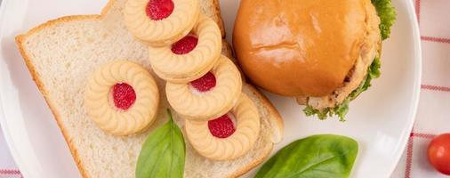 Bread slices with cookies and vegetables and a burger photo