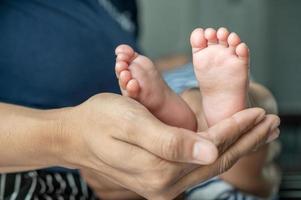 manos de las madres sosteniendo los pies del bebé foto