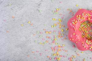 Half a strawberry donut decorated with icing and sprinkles photo