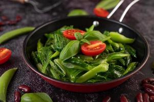 Stir-fried kale in a pan with tomatoes photo