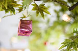 Close-up de una caja de regalo rosa colgando del árbol de Navidad foto