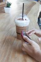 Woman holding a phone with an iced coffee photo