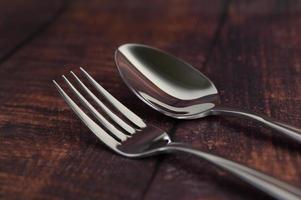 Tenedor y cuchara de acero inoxidable sobre una mesa de madera