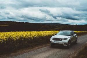 mallorca, españa, 2020 - silver range rover en una carretera un campo de flores amarillas foto