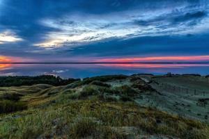 Body of water and dunes during sunset photo