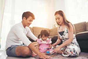 niño con sus padres jugando en el suelo en casa foto