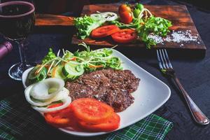 Bistec a la parrilla y vino tinto en la mesa foto