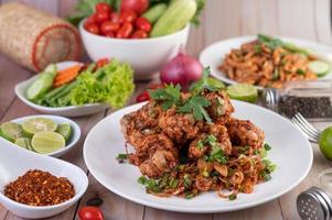 Spicy minced chicken on a plate with cucumber, lettuce and side dishes on wooden table photo