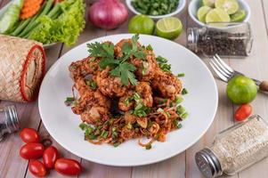 Spicy minced chicken on a plate with cucumber, lettuce and side dishes on wooden table photo