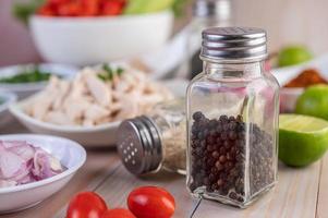 Pepper shaker on wooden table with fresh vegetables photo