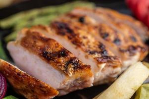 Chicken steak with salad vegetables on a black plate photo