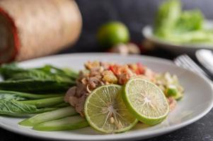 Ensalada picante de cerdo con lima sobre una cama de verduras foto