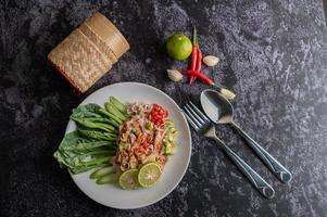 Ensalada picante de cerdo con lima y verduras y acompañamientos foto