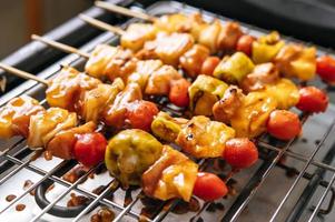 BBQ grill with a variety of meats, tomato and peppers