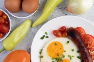 plato de desayuno con huevos fritos, tomates, salchicha china y champiñones foto