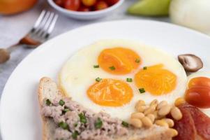 Fried eggs, sausage, minced pork, bread and red beans photo