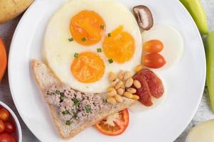 Fried eggs, sausage, minced pork, bread and red beans photo