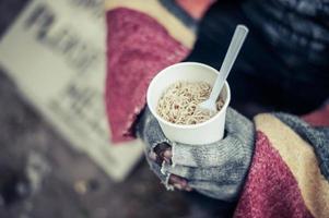 Person sits wrapped in cloth and eating noodles photo