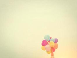 Hands holding colorful balloons in the sunshine of summer photo