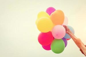 Hands holding colorful balloons in the sunshine of summer photo