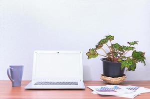 computadora portátil y flor en el escritorio foto