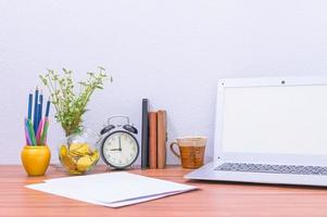 computadora portátil, taza y flor en el escritorio foto