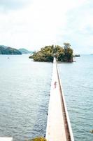 Person walking on a bridge to an island photo