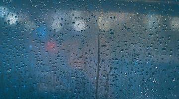 Gotas de lluvia en la ventana del coche. bokeh borroso abstracto de la luz del tráfico y del coche. foto