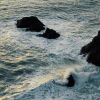 olas del mar rompiendo en las rocas foto