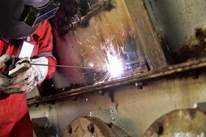 Welder in red suite welding the steel casing photo