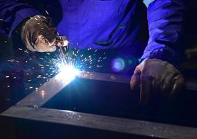 Welder in blue uniform welding the workpiece photo