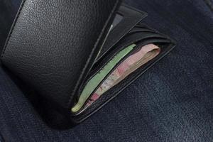 billetera negra con dinero baht. foto