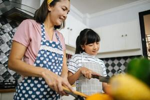 mamá y su hija se ayudan en la cocina de casa foto