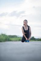 Close-up of young female runner tying her shoes photo