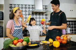 Happy family cutting vegetables together in their kitchen photo