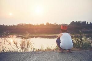 niño triste sentado junto al agua foto