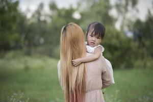 Mother and little daughter playing together in a meadow photo