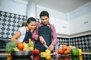 Happy young couple preparing food for cooking in kitchen at home photo