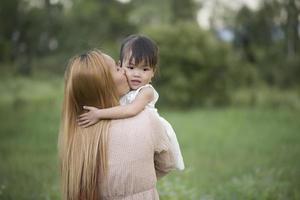 Mother and little daughter playing together in a meadow photo
