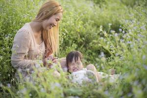 Mother and little daughter playing together in a grassy meadow photo
