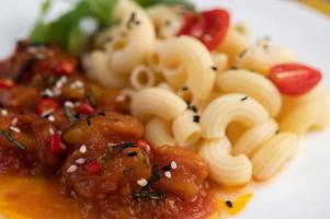 Stir-fried macaroni with tomato, chili, pepper seeds and basil photo