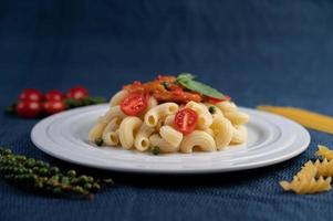 Stir-fried macaroni with tomato, chili, pepper seeds and basil photo