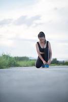 Young female runner ties her shoes outdoors photo