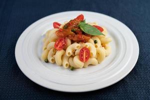 Stir-fried macaroni with tomato, chili, pepper seeds and basil photo