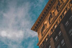 Esquina del edificio marrón con nublado cielo azul foto